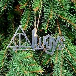 May include: A silver-toned metal ornament featuring the word Always in a stylized font, with the letter A replaced by a triangular Deathly Hallows symbol containing a circle and a vertical line, suspended by a thin tan twine string.