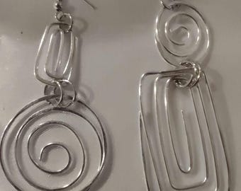 May include: A pair of silver-toned dangle earrings. One earring features a spiral design below a rectangular shape, while the other has a spiral above a rectangular shape. The earrings have a hook closure.