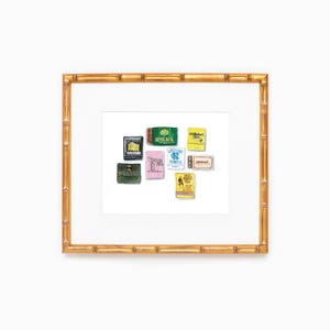 May include: A framed illustration of nine vintage matchbook covers. The matchbooks feature various designs, including a green tree, a yellow and blue logo, and a red and white logo. The matchbooks are arranged in a grid pattern.