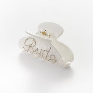 Add a touch of bridal sparkle to your special day with our pearlised diamanté “Bride” claw clip — the perfect accessory for any bride-to-be! Grab your girls and get hen party ready with our simply stunning, on trend, bride claw clip!