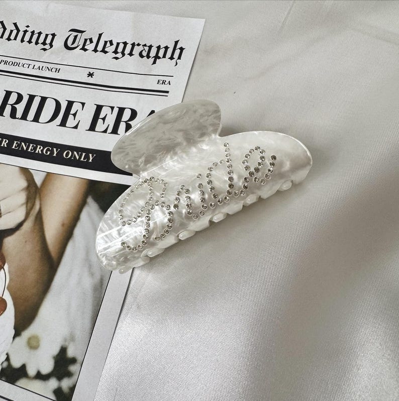 Add a touch of bridal sparkle to your special day with our pearlised diamanté “Bride” claw clip — the perfect accessory for any bride-to-be! Grab your girls and get hen party ready with our simply stunning, on trend, bride claw clip!