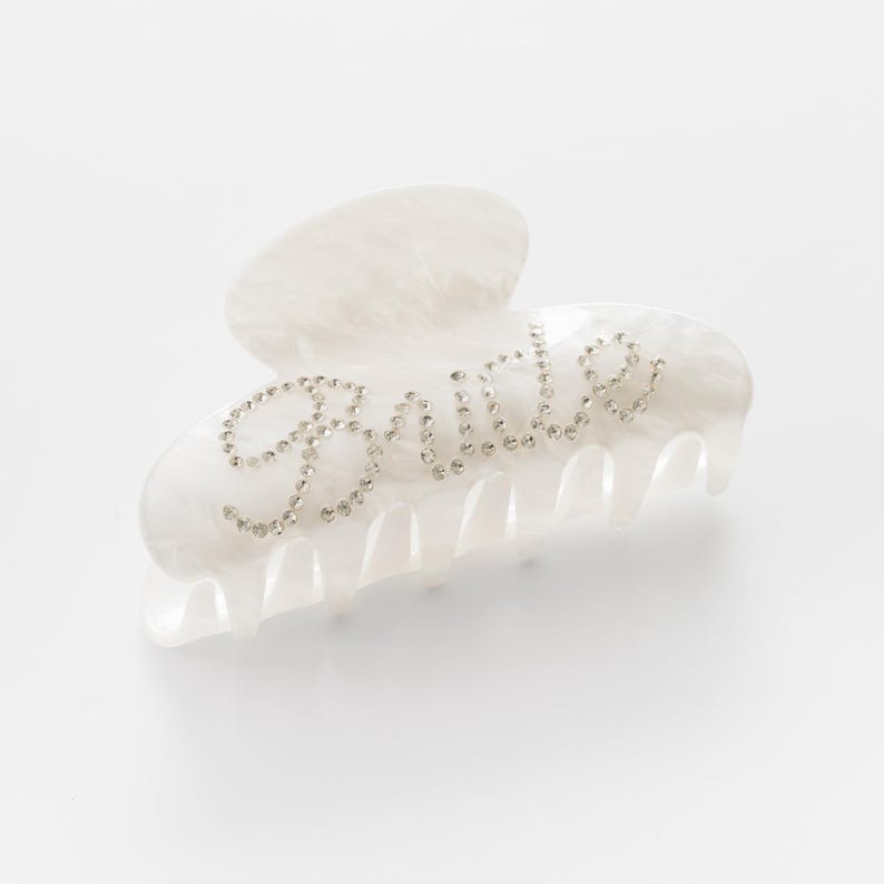 Add a touch of bridal sparkle to your special day with our pearlised diamanté “Bride” claw clip — the perfect accessory for any bride-to-be! Grab your girls and get hen party ready with our simply stunning, on trend, bride claw clip!