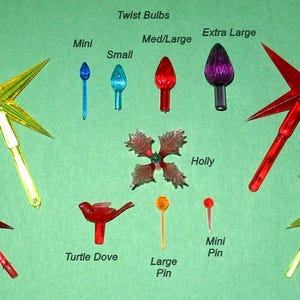 May include: Assortment of Christmas light bulbs and decorative elements on a green background. Includes star-shaped toppers (4 inch and 2 3/4 inch), various bulb sizes, a holly decoration, a turtle dove, and pin-style lights.