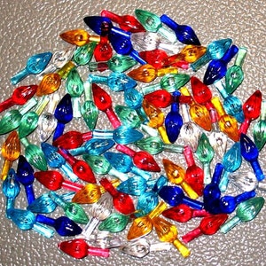 May include: A large assortment of colorful Christmas light bulbs. The bulbs are in various colors, including red, green, blue, yellow, and clear. The bulbs are all in the shape of a teardrop.