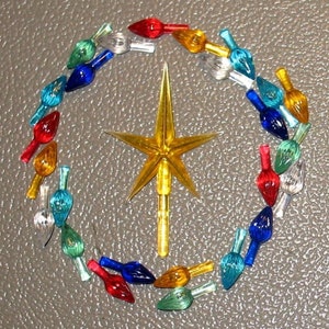 May include: A collection of colorful Christmas tree lights arranged in a circle around a gold star ornament. The lights are in various colors, including red, green, blue, yellow, and clear.
