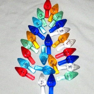 May include: Assortment of colorful Christmas tree light bulbs in various colors, including red, blue, green, yellow, and clear. The bulbs are arranged in a tree shape.