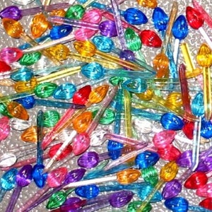 May include: A large assortment of colorful Christmas light bulbs. The bulbs are all clear glass with a variety of colors, including red, green, blue, yellow, and purple. The bulbs are all in the shape of a teardrop and have a small metal tip at the bottom.