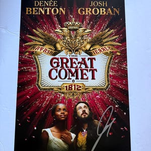 Puede incluir: Un póster rojo y dorado para el musical de Broadway "The Great Comet of 1812" con los actores Denée Benton y Josh Groban. El póster tiene una firma en la esquina inferior derecha.