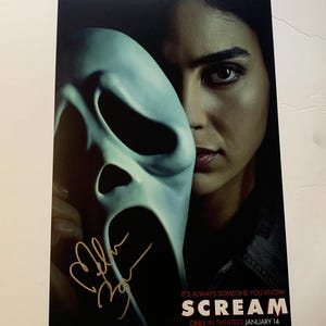 May include: A movie poster for the horror film "Scream" featuring a woman with a Ghostface mask covering half of her face. The text on the poster reads "It's always someone you know" and "Scream" in red letters. The poster also includes the text "Only in cinemas January 14".