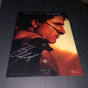 May include: A movie poster for Dune: Part Two, featuring Timothée Chalamet as Paul Atreides. The poster is signed in silver marker. The text on the poster reads "Dune: Part Two", "Only in Theaters 03.01.24", "Filmed for IMAX", and "PG-13".