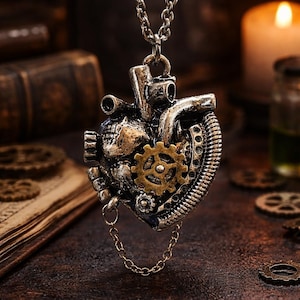 以下が含まれることがあります： 歯車や機械的な要素を取り入れた、詳細な金属製のハートデザインの、スチームパンクスタイルのペンダントネックレス。ペンダントはシルバーチェーンから吊り下げられ、下部には小さなゴールドチェーンが付いています。ハートはシルバーとブロンズの色合いです。