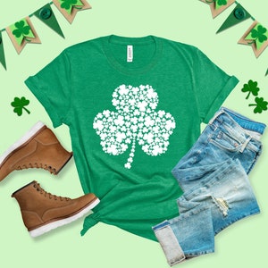 K&ouml;nnte beinhalten: Ein gr&uuml;nes T-Shirt mit einem wei&szlig;en Kleeblatt-Design aus kleineren Kleebl&auml;ttern. Das Kleeblatt ist ein Symbol f&uuml;r Gl&uuml;ck und wird oft mit St. Patrick's Day in Verbindung gebracht.