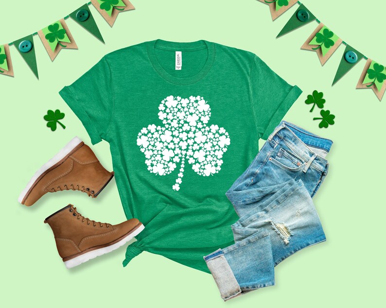 K&ouml;nnte beinhalten: Ein gr&uuml;nes T-Shirt mit einem wei&szlig;en Kleeblatt-Design aus kleineren Kleebl&auml;ttern. Das Kleeblatt ist ein Symbol f&uuml;r Gl&uuml;ck und wird oft mit St. Patrick's Day in Verbindung gebracht.