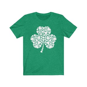 K&ouml;nnte beinhalten: Ein gr&uuml;nes T-Shirt mit einem wei&szlig;en Kleeblatt-Design, das aus kleineren Kleebl&auml;ttern besteht. Das Kleeblatt ist ein Symbol f&uuml;r Gl&uuml;ck und wird oft mit Irland in Verbindung gebracht.