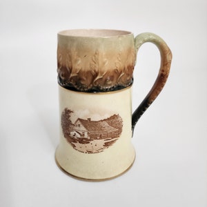 May include: A ceramic mug with a brown and green design. The mug features a picture of a house with the text "First House of Bethlehem, PA".
