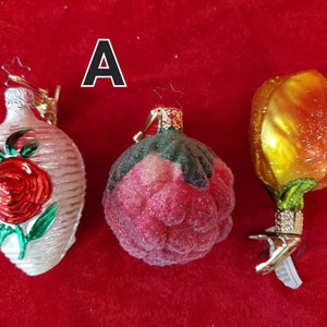 May include: Three glass Christmas ornaments with a red rose, a pink rose, and a yellow tulip design. The ornaments are all hand-blown and have a vintage look.