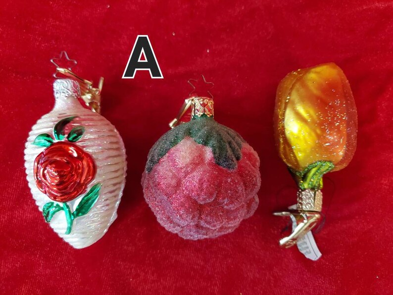 May include: Three glass Christmas ornaments with a red rose, a pink rose, and a yellow tulip design. The ornaments are all hand-blown and have a vintage look.