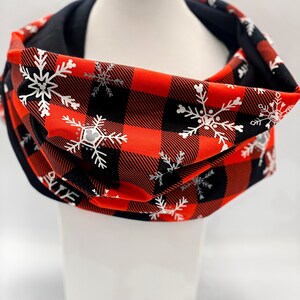 May include: Red and black buffalo plaid infinity scarf with white snowflake pattern.