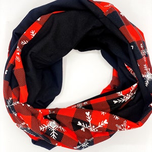 May include: A red and black infinity scarf with a white snowflake pattern. The scarf is made of a soft, comfortable fabric and is perfect for keeping warm in the winter.