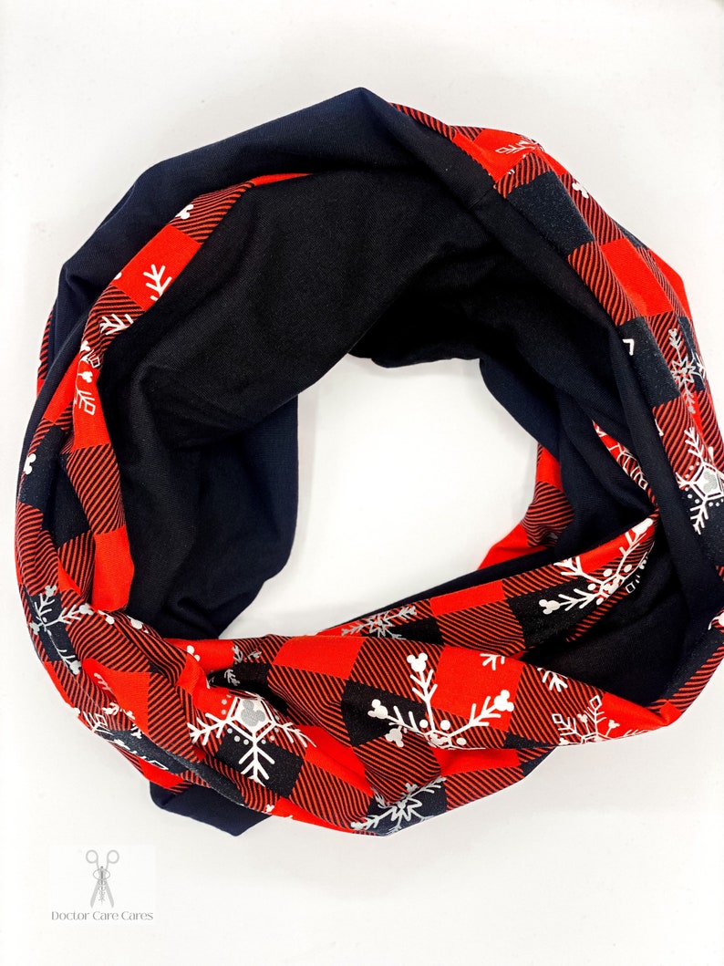 May include: A red and black infinity scarf with a white snowflake pattern. The scarf is made of a soft, comfortable fabric and is perfect for keeping warm in the winter.