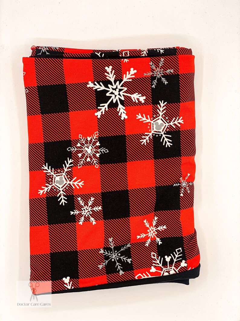 May include: Red and black buffalo plaid fabric with white snowflakes and a Mickey Mouse silhouette in each snowflake.