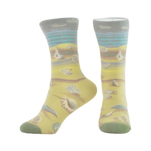 May include: A pair of yellow socks with a seashell pattern. The socks have a light grey band at the top with a blue stripe and a white cloud design.