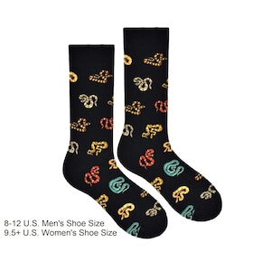 Peut inclure: Une paire de chaussettes noires avec un motif de serpent coloré. Les chaussettes sont présentées sur un fond blanc. Pointures hommes US 8-12. Pointures femmes US 9.5+.