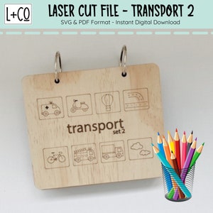 May include: A wooden board with a ring binder, featuring illustrations of various modes of transportation, including an ambulance, scooter, hot air balloon, bicycle, fire truck, and delivery truck. The board is labeled "transport set 2". A cup of colored pencils is shown in the lower right corner.