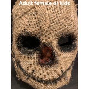 Puede incluir: Una m&aacute;scara de arpillera con agujeros negros para los ojos y una sonrisa cosida. El &aacute;rea de la nariz tiene un dise&ntilde;o rojo texturizado. El texto "Adult female or kids" est&aacute; en la parte superior de la imagen. Esta m&aacute;scara es adecuada para Halloween o eventos de disfraces.
