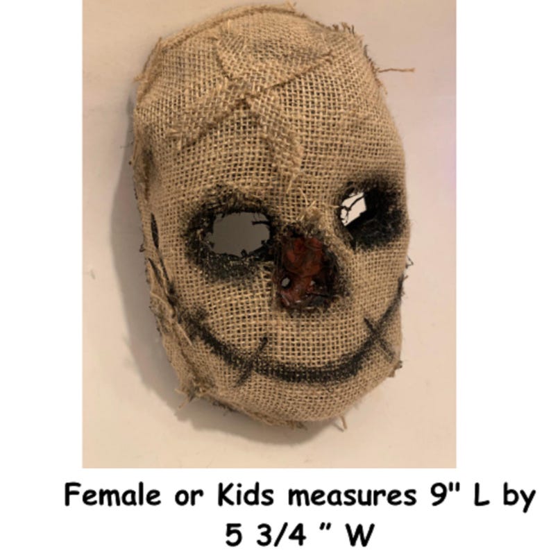 Puede incluir: Una m&aacute;scara de arpillera con costuras, detalles negros para los ojos y la boca, y una nariz marr&oacute;n rojiza. La m&aacute;scara mide 22,86 cm de largo por 14,61 cm de ancho. El texto en la imagen dice: Female or Kids measures 9" L by 5 3/4 " W.