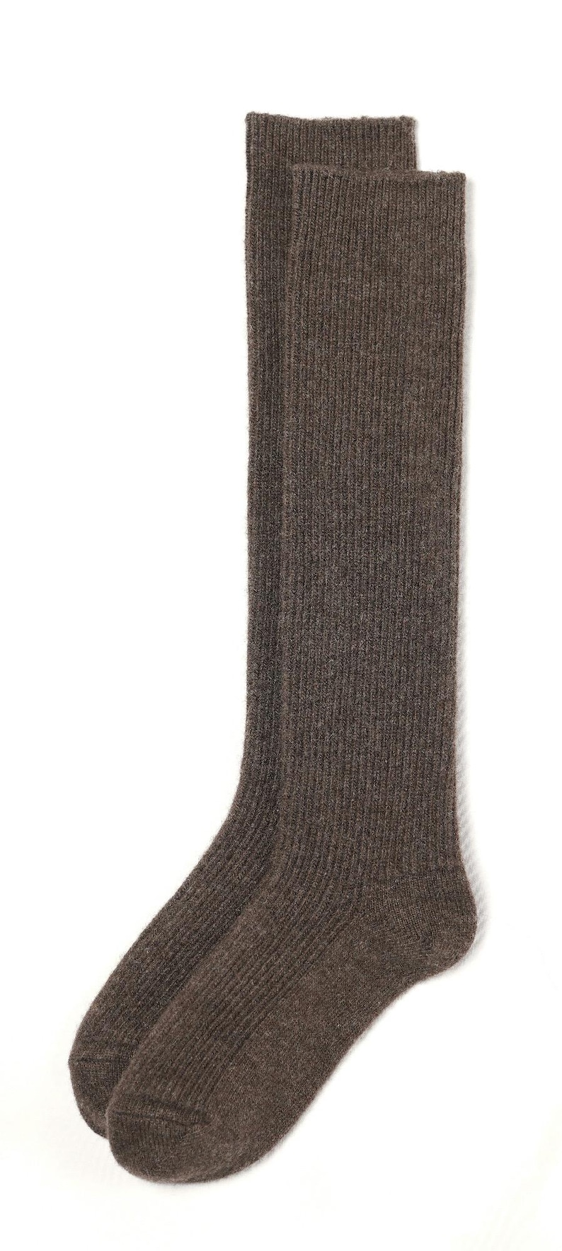 May include: A pair of brown knee-high socks made of a soft, fuzzy material. The socks have a ribbed texture.