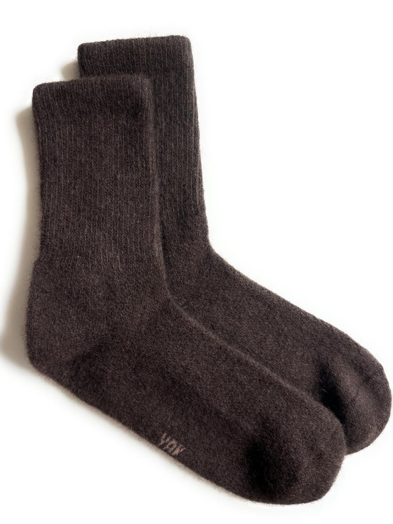 May include: A pair of dark brown socks, likely wool or a similar material, with a ribbed texture. The socks are folded and displayed against a white background. The brand name "YOK" is visible on the side of one sock.