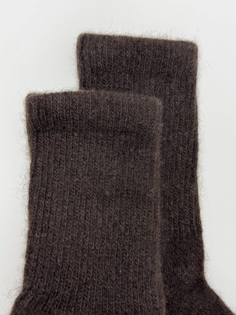 May include: Close-up of two brown socks. The socks are made of a soft, textured material, with a ribbed knit pattern. The cuffs are folded over, and the socks appear to be unworn.