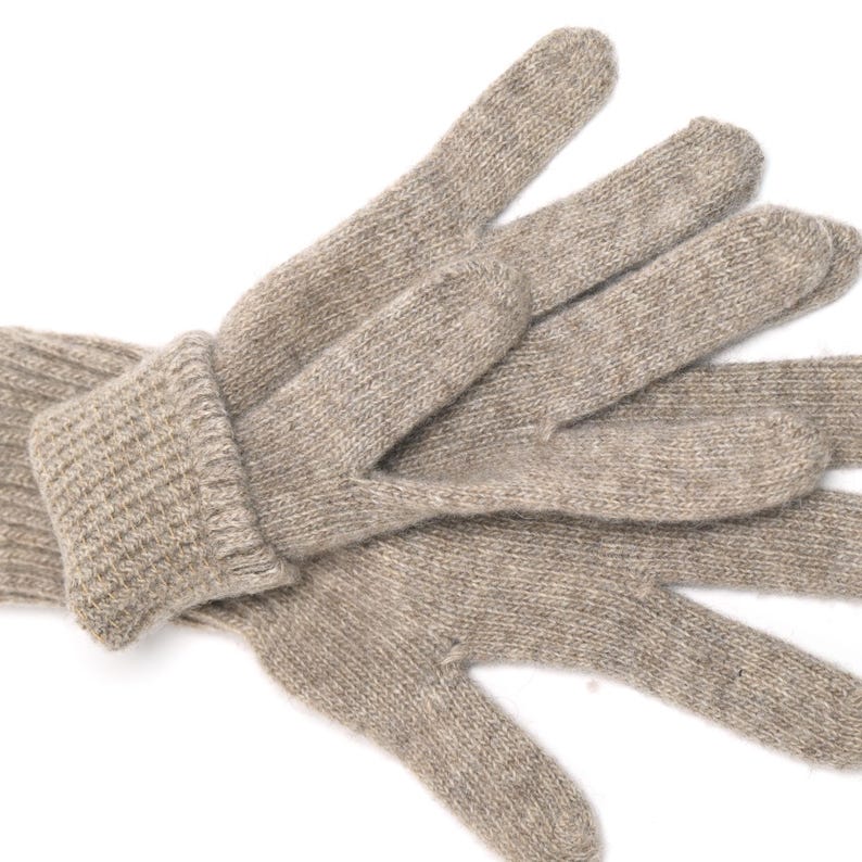 May include: A pair of beige knitted gloves with a ribbed cuff. The gloves are made of a soft, warm material and are perfect for keeping your hands warm in cold weather.