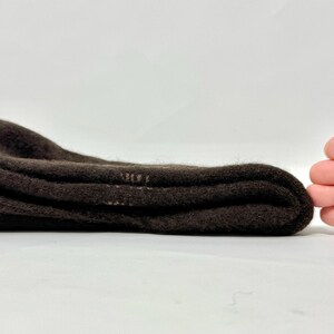 May include: Folded brown socks, likely wool or a similar material, are stacked neatly. The socks are a solid, dark brown color and appear soft. The image is taken on a white background.