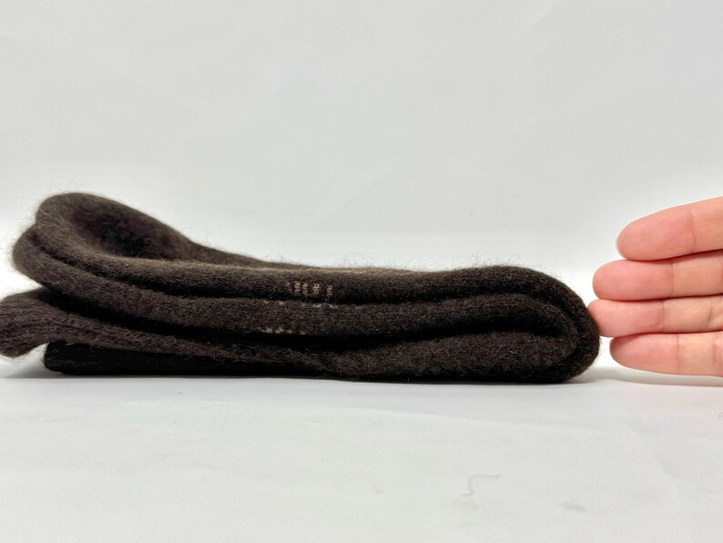 May include: Folded brown socks, likely wool or a similar material, are stacked neatly. The socks are a solid, dark brown color and appear soft. The image is taken on a white background.