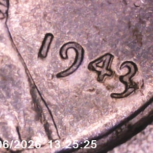 May include: Close-up of a silver coin with the date "1943" prominently displayed. The coin's surface shows wear and texture, with the numbers appearing in a bold, slightly worn font. The date is the primary focus.