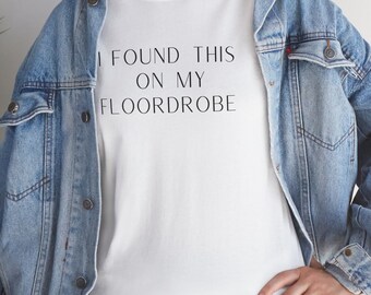 Puede incluir: Camiseta blanca con el texto "I found this on my floordrobe" impreso en la parte delantera. La camiseta la lleva puesta una persona que lleva una chaqueta vaquera.