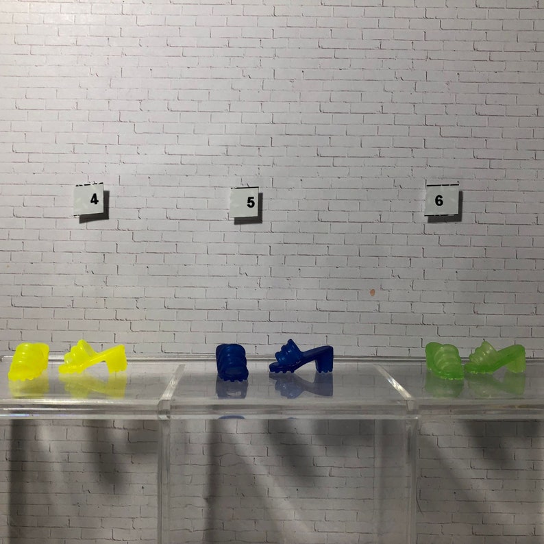 Puede incluir: Tres pares de sandalias de gelatina de colores. El primer par es amarillo, el segundo par es azul y el tercer par es verde.