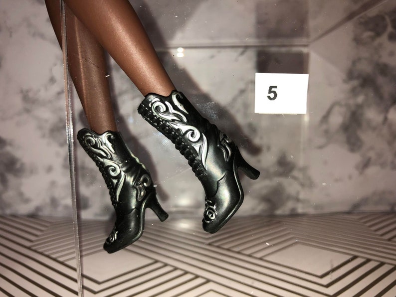 May include: A pair of black heeled boots with silver floral designs. The boots have a pointed toe and a high heel.