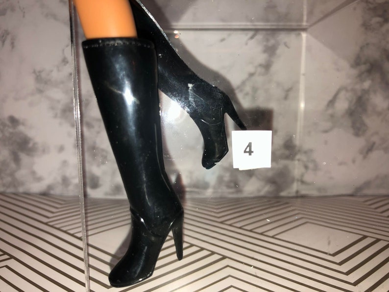 May include: A pair of black knee-high boots with high heels. The boots are made of a shiny material and have a pointed toe.