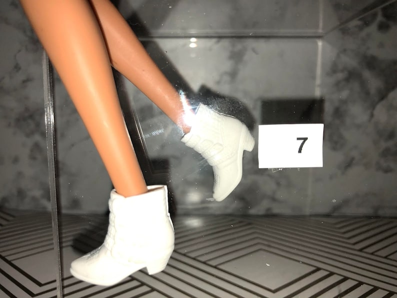 May include: A pair of white ankle boots with a pointed toe and a small heel. The boots are made of a soft, textured material. The number 7 is visible on a white label.
