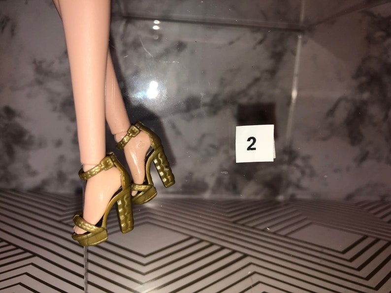 May include: A pair of gold high-heeled sandals with ankle straps. The sandals have a textured platform and a chunky heel.