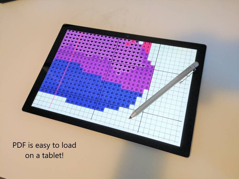 May include: A tablet screen displaying a digital cross-stitch pattern with pink, purple, and blue squares. A stylus pen is lying on the screen. The text "PDF is easy to load on a tablet!" is displayed below the screen.