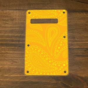 May include: A yellow guitar pickguard with a white paisley pattern.
