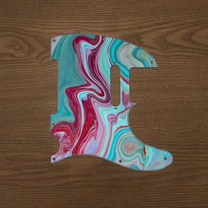 May include: A teal, pink and white guitar pickguard with a marbled swirl pattern.