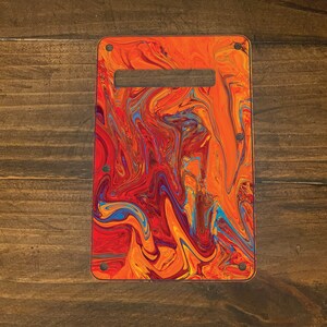 May include: A guitar pickguard with a colorful abstract design featuring swirls of red, orange, yellow, and blue paint.