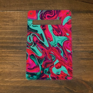 May include: A guitar pickguard with a swirling abstract pattern in shades of pink, teal, and black.