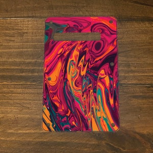 May include: A colorful guitar pickguard with a swirling abstract pattern in shades of pink, orange, teal, and black.
