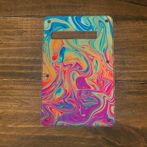 May include: A colorful guitar pickguard with a swirling, abstract pattern in shades of blue, green, yellow, orange, and pink.